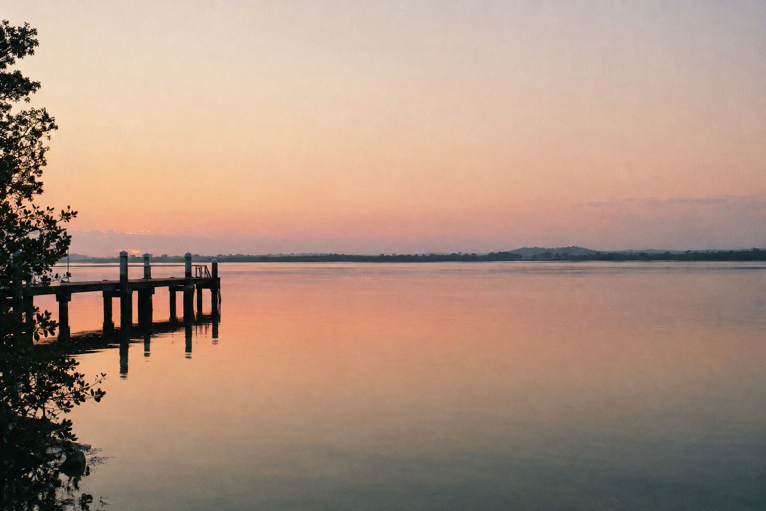 A still river at dawn with a jetty and a peach sky